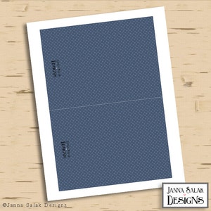 May include: A blank card with a blue polka dot pattern. The card is folded in half and has a white border. The text "Janna Salak Designs" is printed on the front of the card.