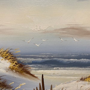 Op de afbeelding: Een schilderij van een zeezicht met een zandstrand, blauw water en een paar witte vogels die in de lucht vliegen. Het schilderij is gemaakt in een realistische stijl met zichtbare penseelstreken.