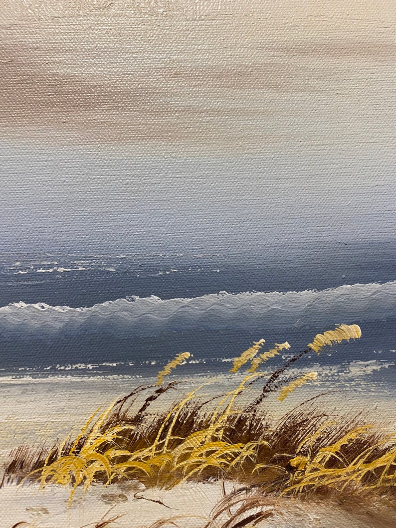 Op de afbeelding: Een schilderij van een zeegezicht met hoog gras op de voorgrond. De lucht is lichtblauw en het water is donkerblauw. Het gras is lichtbruin en geel.