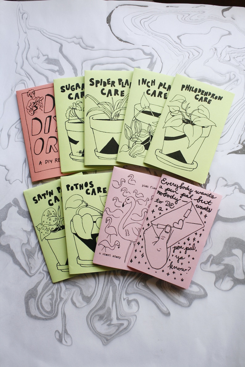 May include: A collection of nine small zines with light green and pink covers featuring black line art illustrations and hand-lettered text. Titles include Sugar Plant Care, Spider Plant Care, Inch Plant Care, Philodendron Care, Satin Pothos Care, Pothos Care, DIY Or Die, Pink Flamingo, and a zine about pen pals.