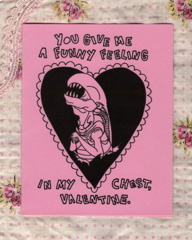 An illustration of a chest burster from the movie Alien, popping out of a heart with it's mouth open and wringing it's little hands. Text reads, "You give me a funny feeling in my chest, valentine."