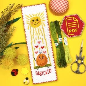 May include: A cross-stitch bookmark with a smiling sun and a smiling orange on a swing. The sun is sending down hearts to the orange. The bookmark is white with a red border and the text "BABYCADO" at the bottom.