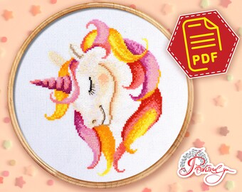 Puede incluir: Un patrón de punto de cruz de un unicornio con un cuerno rosa y una melena rosa, amarilla y naranja. El patrón está en un aro de bordado blanco.