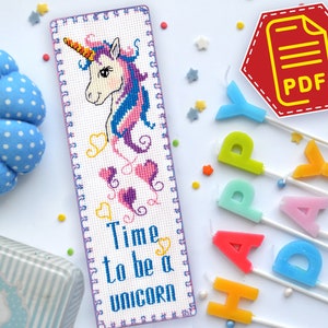 Puede incluir: Un marcapáginas de punto de cruz con un diseño de unicornio colorido y el texto "Time to be a unicorn".