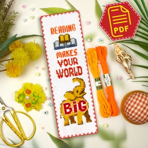 May include: Cross stitch pattern for a bookmark featuring an elephant and the text "Reading makes your world big". The pattern is on white Aida cloth with orange floss.