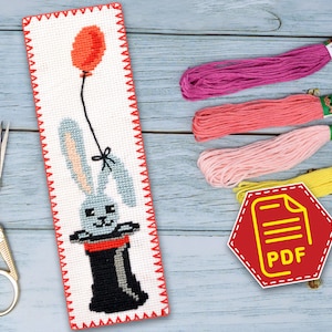 May include: A cross-stitch bookmark pattern featuring a gray rabbit wearing a top hat and holding a red balloon. The pattern is available as a PDF download.