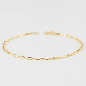 May include: A gold chain bracelet with a delicate, square-link design.
