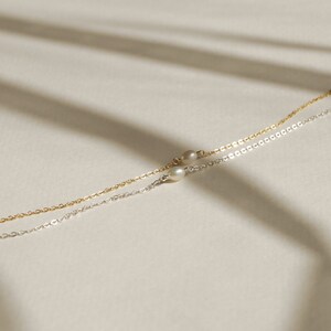 May include: Two delicate necklaces with small pearl accents. One necklace is silver and the other is gold.