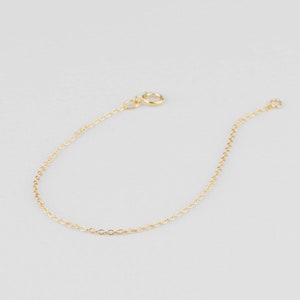 Puede incluir: Un delicado brazalete de cadena dorada con un cierre simple.