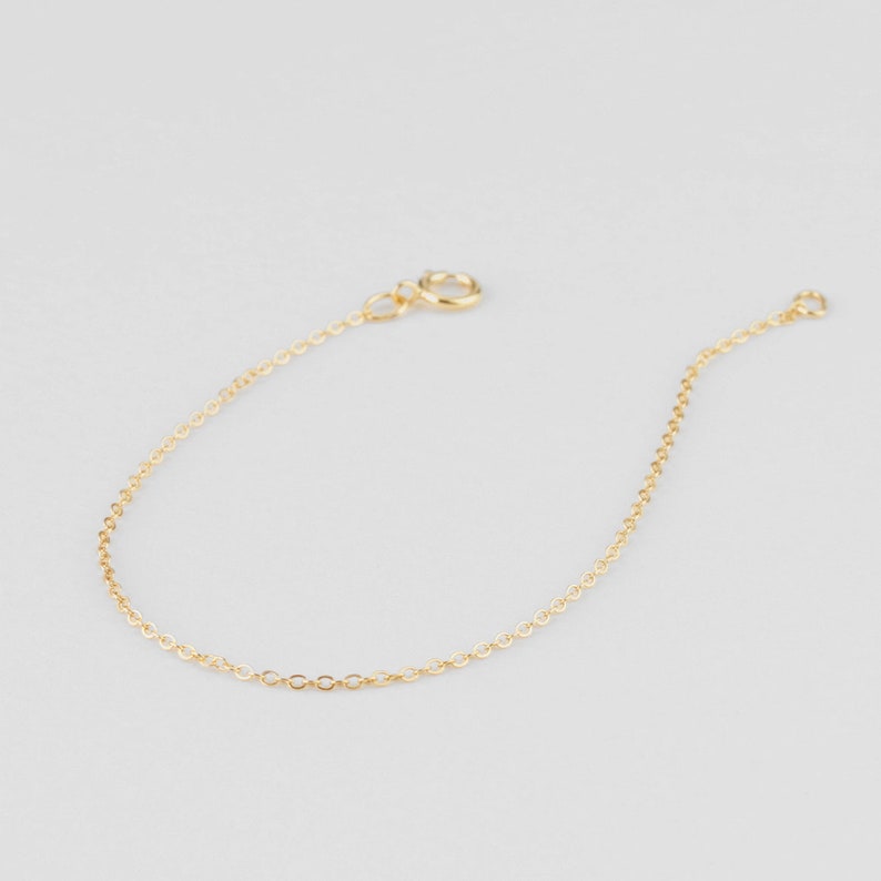 Puede incluir: Un delicado brazalete de cadena dorada con un cierre simple.