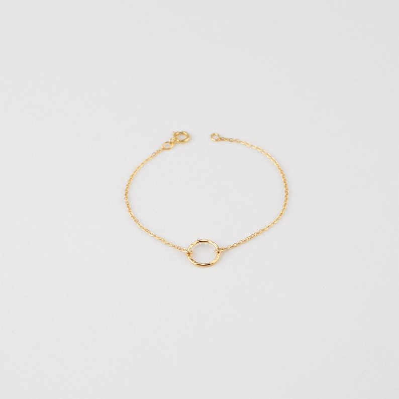 May include: A delicate gold chain bracelet with a simple circle pendant.