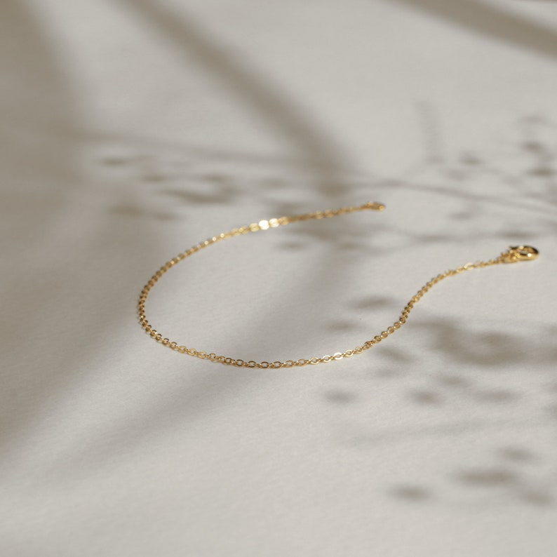 Puede incluir: Un delicado brazalete de cadena dorada con cierre de langosta.