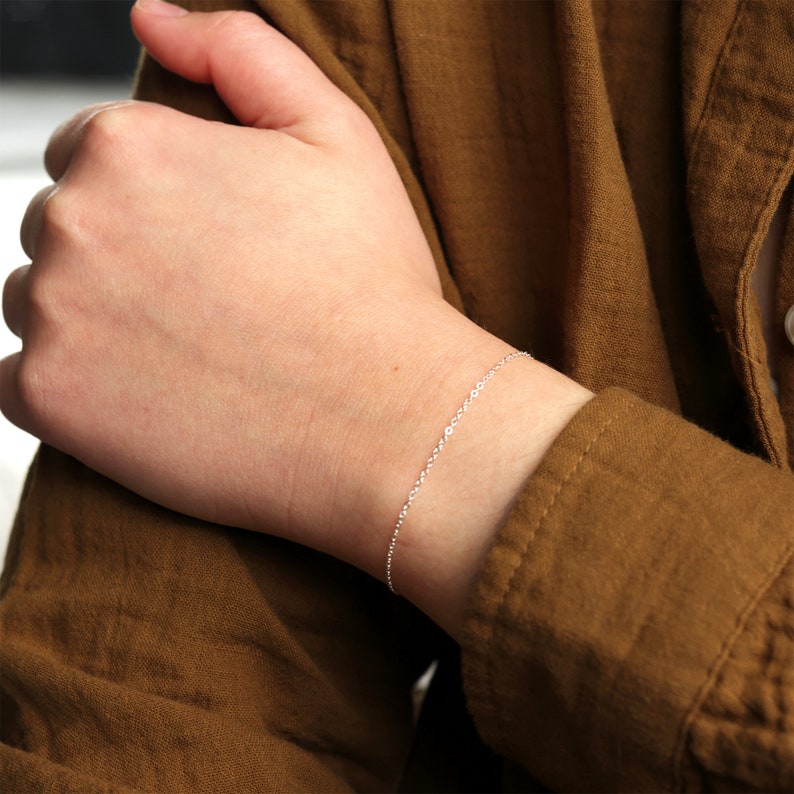 Puede incluir: Un delicado brazalete de cadena de plata en la mu&ntilde;eca de una persona.
