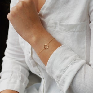 May include: A delicate gold bracelet with a simple circle charm. The bracelet is made of a thin chain and is perfect for everyday wear.