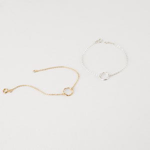 May include: Two delicate bracelets with a simple circle design. One bracelet is gold and the other is silver.