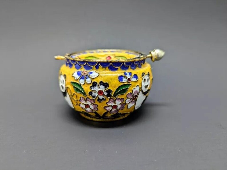 Pu&ograve; includere: Un piccolo vaso in smalto cloisonn&eacute; giallo con un coperchio e un motivo floreale. Il vaso &egrave; decorato con orsi panda bianchi e neri e fiori colorati.