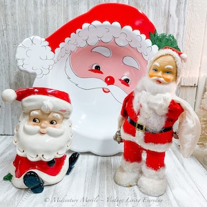 May include: Three vintage Santa Claus figurines. One is a large white ceramic bowl with a red rim and a Santa face. The other two are smaller, one is white with a red hat and the other is red with a white beard.
