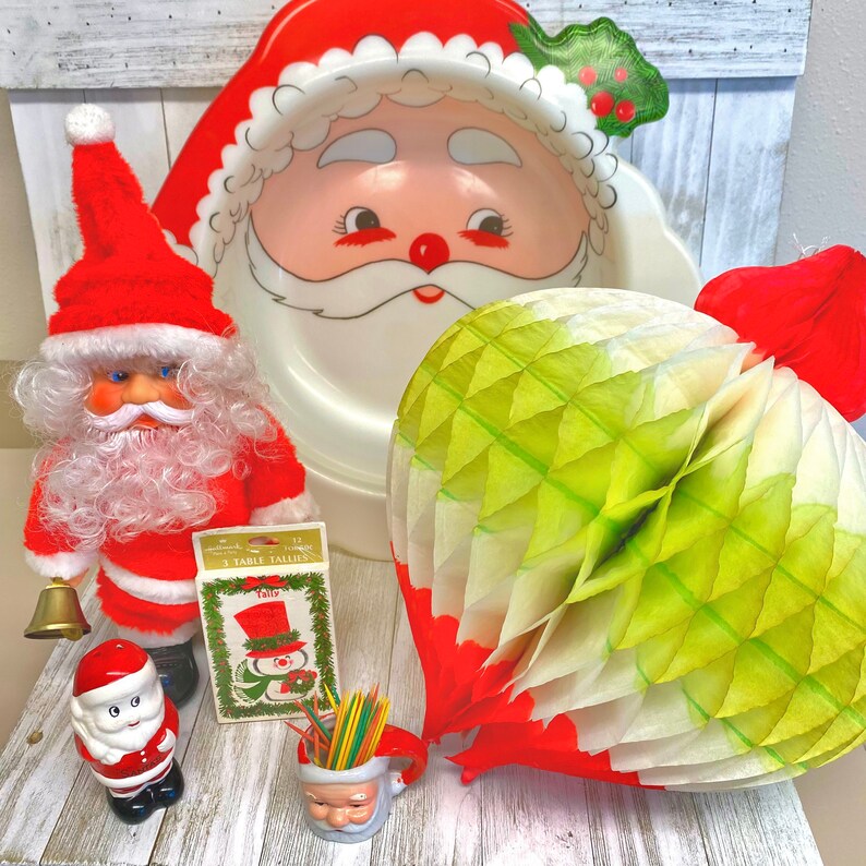 May include: A red and white Santa Claus plate with a green holly design, a red and white Santa Claus doll, a green and white paper honeycomb ball, and a small red and white Santa Claus figurine.