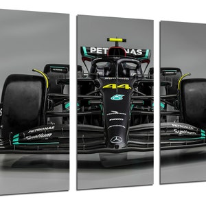 Puede incluir: Un coche de carreras de F&oacute;rmula 1 negro con el n&uacute;mero 44 en el lateral. El coche tiene un logotipo de Petronas Syntium en el lateral y la palabra "PETRONAS" en la parte delantera. El coche est&aacute; sobre un fondo gris.