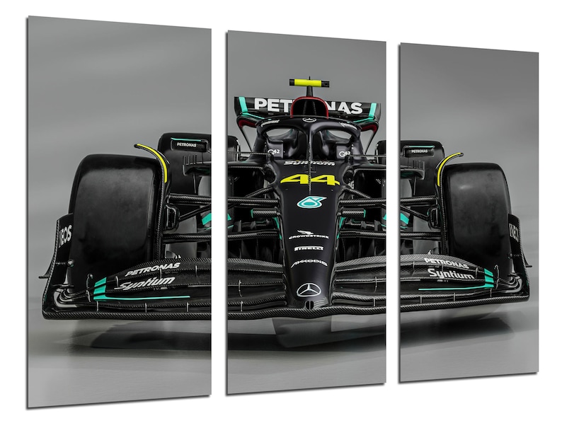 Puede incluir: Un coche de carreras de F&oacute;rmula 1 negro con el n&uacute;mero 44 en el lateral. El coche tiene un logotipo de Petronas Syntium en el lateral y la palabra "PETRONAS" en la parte delantera. El coche est&aacute; sobre un fondo gris.