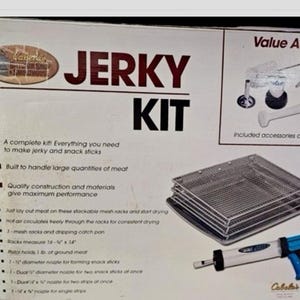 Op de afbeelding: Jerky Kit-doos met de woorden "JERKY KIT" in grote letters. De kit bevat stapelbare gaasrekken, een jerky-pistool en andere accessoires. De doos vermeldt dat de kit is gebouwd om grote hoeveelheden vlees te verwerken.