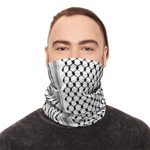 Könnte beinhalten: Eine Person trägt einen Halswärmer mit einem schwarz-weißen geometrischen Muster. Der Halswärmer bedeckt den unteren Teil des Gesichts und den Hals. Die Person trägt ein dunkelgraues T-Shirt.