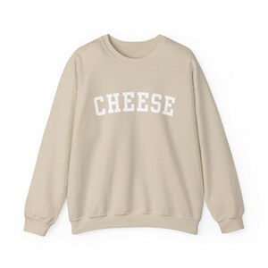 May include: A light beige sweatshirt with the word "CHEESE" printed in white on the front.