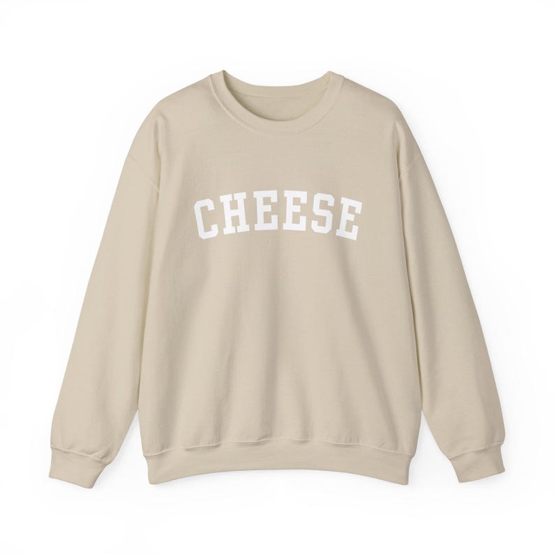 May include: A light beige sweatshirt with the word "CHEESE" printed in white on the front.
