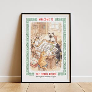 May include: A framed print featuring a watercolor illustration of cats playing mahjong. The artwork includes the text "WELCOME TO" and "THE CRACK HOUSE" with the tagline "Where friends bond and tea spills". The print has a green border.