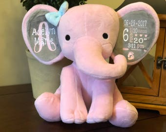 May include: Pink plush elephant stuffed animal with gray ears. The ears are embroidered with the name "Adelyn Marie" and the date "06-29-2017", weight "6 pounds 10 ounces", and time "3:11 pm".