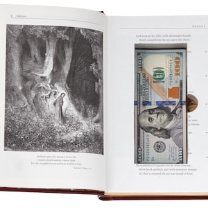 May include: A hollowed-out book titled Inferno with a black and white illustration of a figure in a forest on the left page and a rectangular cutout on the right page containing a folded one hundred dollar bill.
