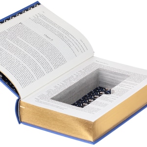 May include: A hollowed-out hardcover book titled War and Peace with a rectangular cutout in the center of the pages. The interior of the cutout features a dark blue fabric lining with a white pattern. The book has gold-gilded page edges.