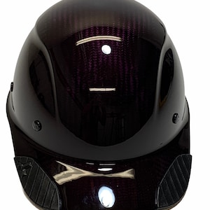 May include: A black hard hat with a carbon fiber finish and a black visor. The hard hat has a white light on the front.
