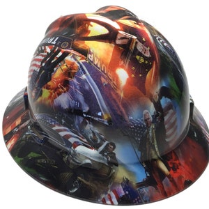 May include: A hard hat with a wrap-around graphic featuring patriotic imagery, including the American flag, historical figures, and a car chase scene. The hat has a glossy finish and a wide brim.