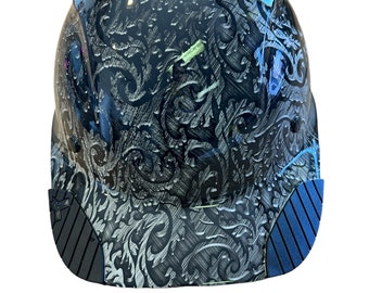 Può includere: Un casco nero con un design a motivi blu e argento. Il casco ha una visiera nera con un design testurizzato.