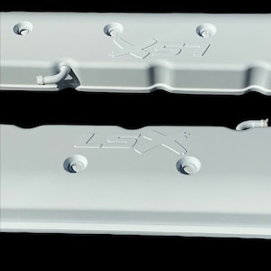 May include: Two white engine valve covers with the text "LSX" embossed on them. The covers are made of metal and have a smooth, matte finish.