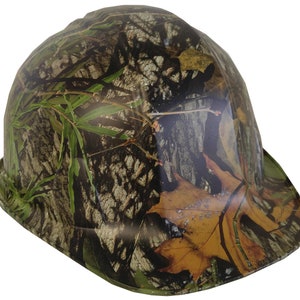 May include: A camouflage hard hat with a brown, green, and tan pattern. The hat has a wide brim and a rounded crown.