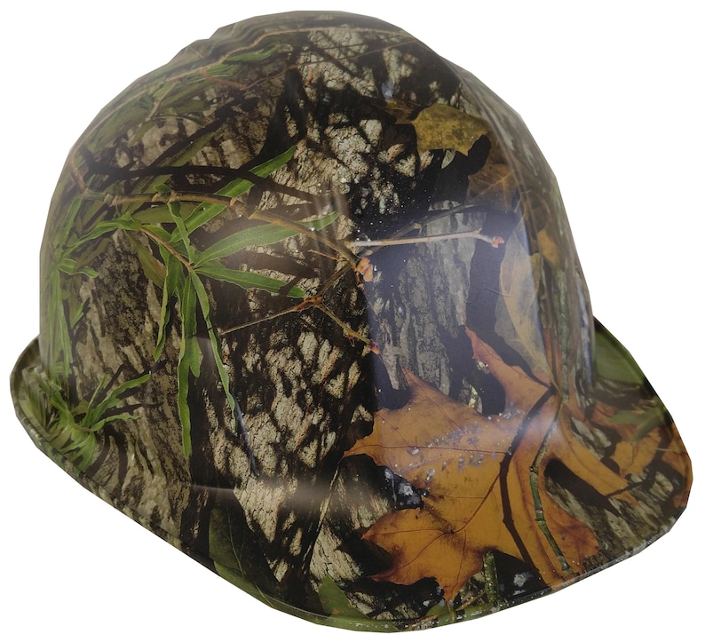 May include: A camouflage hard hat with a brown, green, and tan pattern. The hat has a wide brim and a rounded crown.