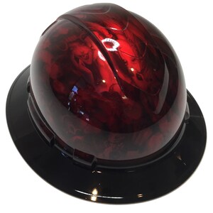 Puede incluir: Un casco de seguridad rojo con una visera negra. El casco tiene un diseño personalizado con aerógrafo con un esquema de color rojo y negro.