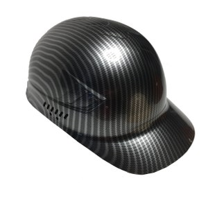 Peut inclure: Casque de sécurité noir et gris en fibre de carbone avec visière. Le casque présente un motif texturé et des trous d'aération sur le côté. Le casque est conçu pour protéger la tête des chocs.