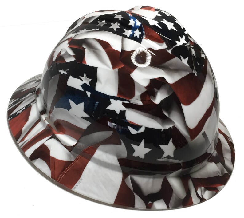Puede incluir: Un casco blanco con un dise&ntilde;o de bandera americana roja, blanca y azul. El dise&ntilde;o de la bandera es un primer plano de la bandera americana con las estrellas y las rayas.