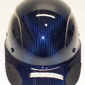 May include: A blue hard hat with a carbon fiber pattern and a black brim. The hat has a white stripe on the front and back.