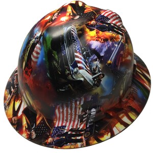 May include: A hard hat with a patriotic design featuring American flags, a vintage car, and the word "LIBERTY". The hat has a wrap-around design with a mix of red, white, and blue colors, and the word "TRUMP" is visible.