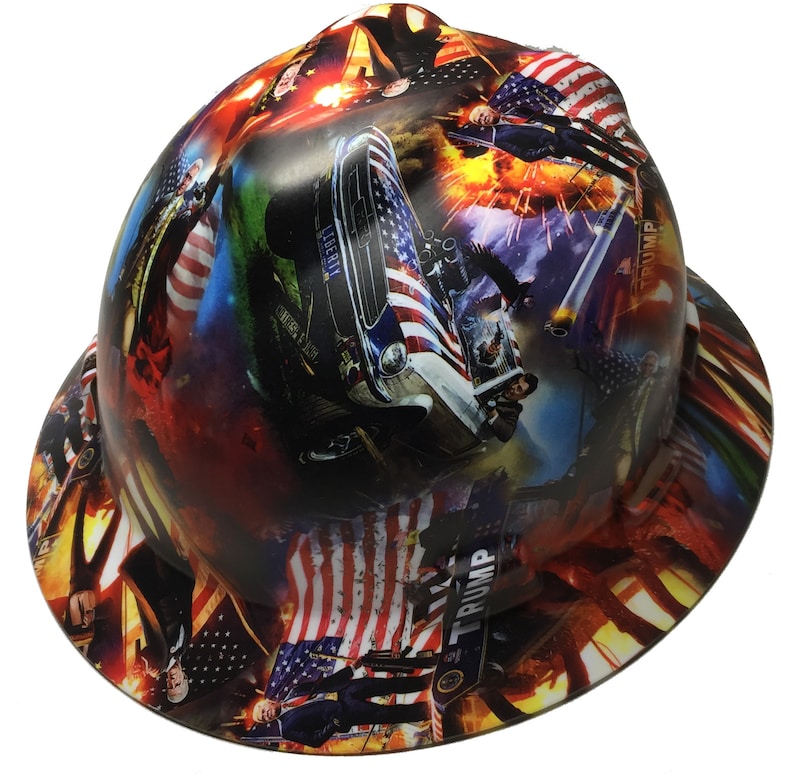 May include: A hard hat with a patriotic design featuring American flags, a vintage car, and the word "LIBERTY". The hat has a wrap-around design with a mix of red, white, and blue colors, and the word "TRUMP" is visible.