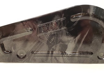 May include: A black metal plate with a textured, abstract design. The plate has a curved edge and two holes on the bottom. The text "BROWN" is visible in the centre of the plate.