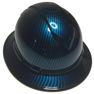 Könnte beinhalten: Ein blauer Helm mit einem Karbonfaser-Muster. Der Helm hat einen schwarzen Rand und ein schwarzes Band um die Oberseite.