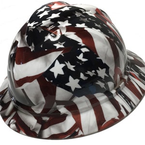 Puede incluir: Un casco de seguridad con un dise&ntilde;o de bandera estadounidense. El casco es blanco con rayas rojas y azules y estrellas blancas.