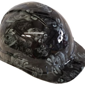 Könnte beinhalten: Ein schwarzer Schutzhelm mit einem Totenkopf-Grafikdesign. Der Helm hat ein graues und weißes Totenkopf-Muster.