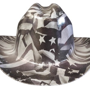 Puede incluir: Un sombrero vaquero blanco y negro con un patrón de estrellas y rayas. El sombrero está hecho de un material brillante.