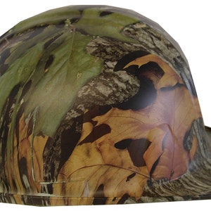 May include: A camouflage hard hat with a wide brim. The hat is made of a durable plastic and features a leafy camouflage pattern in shades of green, brown, and tan.